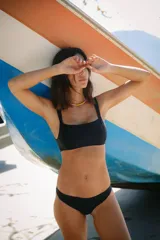 Conjunto de bikini negro de lycra mate premium, corpiño con recortes y escote cuadrado, breteles anchos y bombacha vedetina.