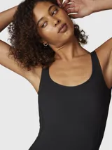 Enterito largo de una pieza color negro, con tirantes anchos, escote redondo y piernas con corte ligeramente acampanado. Confeccionado en tejido elástico con costuras anatómicas que se ajustan al cuerpo.