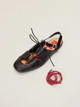 Sandalias planas tipo slingback de cuero marrón, con diseño delantero calado, cierre de cordones y tira trasera ajustable con hebilla.