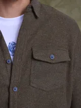 Overshirt de textura tipo tweed en color marrón, con cuello clásico, cierre frontal de botones y bolsillo en el pecho.