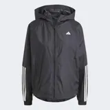 Campera corta vientos Adidas WIND.RDY Hyperglam negra con capucha, cierre frontal, bolsillos con cierre, mangas largas con tres tiras blancas y logo blanco en el pecho. Confeccionada con materiales reciclados.