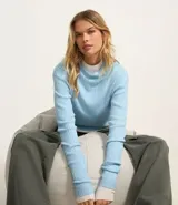 Sweater celeste de punto acanalado con cuello alto y mangas largas.