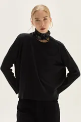 Sweater negro de punto liso, escote redondo y calce cómodo. Las mangas son largas y presentan un tejido acanalado en los puños.