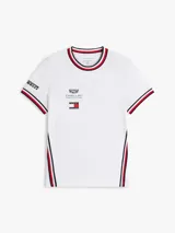 Remera de algodón Tommy Hilfiger en colaboración con Cadillac Formula 1 Team, de corte holgado y largo cropped. Presenta cuello redondo con ribetes tricolores, mangas cortas con ribetes a juego y cinta distintiva en los laterales. Incluye logos de Cadillac, Tommy Hilfiger y Pirelli estampados en el pecho y mangas.