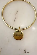 Pulsera esclava rígida de metal dorado con medalla colgante grabada con el texto "Shinyuu".