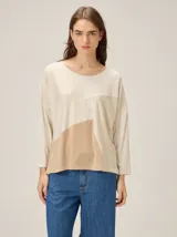 Remera de silueta relajada con diseño de paneles en tonos beige y crema, cuello redondo y mangas tres cuartos.
