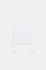 Camiseta de manga larga confeccionada en algodón 100%, con cuello redondo y cierre frontal mediante una hilera de botones.