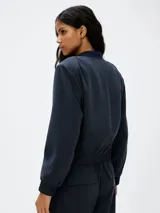 Campera tipo bomber color azul, con cierre frontal, cuello redondo acanalado, bolsillos frontales con solapa y cintura y puños elásticos.