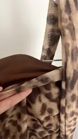 Top corto de un solo hombro, con estampado animal print y corbatín al cuello.