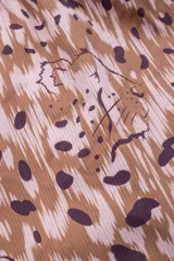 Bombacha de bikini color beige con estampado abstracto en tonos marrones, de tiro alto y cobertura amplia. Incluye cinturón fino con hebilla metálica.