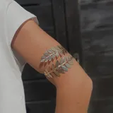 Brazalete dorado y plateado con diseño de hojas.