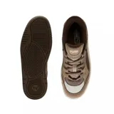 Championes urbanos Puma modelo 180, con diseño inspirado en el skate de los años 90. Presentan una combinación de tonos beige y marrón, confeccionados en una mezcla de gamuza y malla técnica. Cuentan con una suela de goma robusta en color crema y detalles de la marca en la lengüeta y laterales.