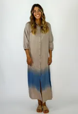 Vestido camisero largo color beige con degradé azul en el ruedo, de corte recto, manga 3/4 y cierre frontal con botones.