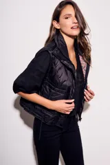 Chaleco negro con cierre frontal y cuello alto, de corte al cuerpo y diseño acolchado. Reversible, con interior a cuadros.