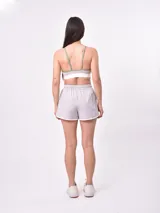 Short deportivo rosado con cintura elástica con cordón de ajuste, ribetes negros y franja lateral en color rosa claro.