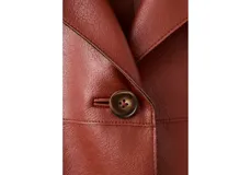 Chaqueta corta color bordó, de manga larga, con cuello camisero, bolsillos frontales con solapa y cierre de botones oscuros.