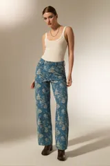 Pantalon de jean de corte recto con estampado floral en tonos claros sobre base azul. Presenta bolsillos funcionales y tiro medio.