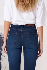 Jean de tiro medio con corte oxford, confeccionado en denim azul oscuro con costuras a contratono. Presenta cierre frontal con botón metálico, bolsillos delanteros y traseros.