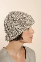 Gorro tejido a mano en punto grueso, con diseño de canalé y textura jaspeada en tonos neutros.