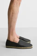 Alpargatas negras de piel con talón plegable, forro interior de piel, horma cuadrada y suela recubierta de yute.