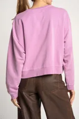 Buzo lila oversize confeccionado en 100% algodón, con cuello redondo, mangas largas y puños y dobladillo acanalados. Presenta un pequeño detalle bordado en el bajo.