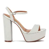 Sandalia de plataforma alta y taco grueso, color dorado brillante con textura glitter. Presenta una tira ancha en la parte delantera y una tira fina ajustable alrededor del tobillo.