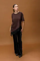 Remera de color marrón con cuello redondo y mangas cortas. Presenta un diseño asimétrico en el ruedo con un delicado detalle de encaje negro aplicado.