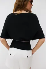 Top de punto color beige con cuello barco y mangas cortas anchas tipo murciélago. Cuenta con cintura entallada con ribete elástico y un cinturón fino de cuero sintético marrón con hebilla metálica dorada.