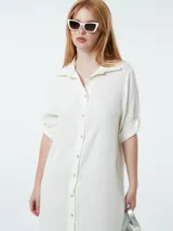 Vestido camisero color crudo, con cuello, botones frontales y mangas 3/4.