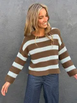 Sweater de punto a rayas horizontales en color marrón y celeste, con cuello redondo a la base y mangas largas.