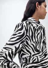 Chaqueta de corte recto con estampado de cebra, cuello de solapa, cierre frontal con botones, manga larga y dos bolsillos de solapa en la parte frontal. Incluye forro interior.