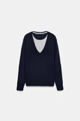 Jersey de punto de manga larga con cuello en V profundo. Presenta un diseño de doble capa con una pieza interior en color gris claro que simula una camiseta debajo del jersey principal en color azul marino.
