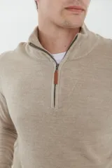 Sweater verde oliva de tejido acrílico con textura similar al cashmere, corte clásico, cuello alto con cierre metálico y tirador de cuerina ecológica.