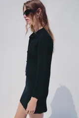Chaqueta de punto color azul marino, con cuello solapa, manga larga y cierre frontal con botones metálicos. Presenta terminaciones en ondas en el bajo y los puños.