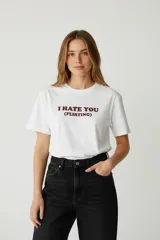 Remera de algodón blanca, corte holgado, con cuello redondo y manga corta. Estampado frontal con texto en color bordó: "I HATE YOU (FLIRTING)".