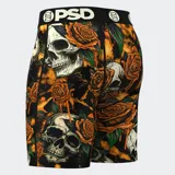 Calzoncillos bóxer de hombre con estampado de calaveras y rosas en tonos naranja y negro. Cuenta con pretina elástica negra con el logo de la marca en blanco, entrepierna de 7 pulgadas y bolsa MicroMesh transpirable.