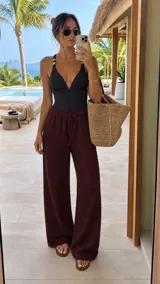 Pantalón tipo palazzo de tiro alto con cintura elástica y cordón ajustable. Confeccionado en tela texturizada con caída fluida y corte amplio.
