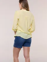 Blusa de gasa bambúla color amarillo, marca Zac & Rachel, con cuello a la base y escote en V con botones frontales. Presenta diseño delantero plisado y mangas largas con sistema de ajuste mediante presilla.