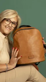 Mochila de tamaño mediano confeccionada en símil cuero color suela, con cierre principal de gran capacidad, asa de mano superior y correas regulables. Incluye bolsillo oculto en la parte trasera y detalles metálicos.
