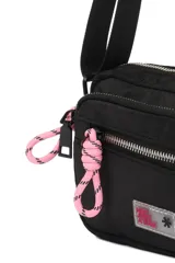 Bandolera color lila de poliéster con correa ajustable negra, cierre principal y bolsillo frontal con cierre. Detalle de cordón rosa y logo bordado.