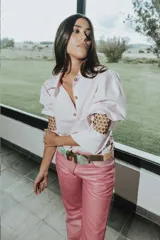 Pantalón de cuero color marrón con estampado abstracto, corte acampanado y abertura en el ruedo.