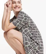Vestido corto en viscosa con estampado de pinceladas en tonos negro, verde y blanco. Tiene cuello solapa, mangas cortas, abotonado delantero y volado en el bajo.