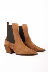 Bota tipo chelsea de gamuza color marrón, con paneles laterales elásticos en color negro, puntera cuadrada y taco bloque de altura media.