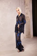 Camisa de corte oversize y holgado, confeccionada en una combinación de tela azul con superposición de encaje negro. Presenta mangas largas, cuello clásico y cierre frontal con botones transparentes.