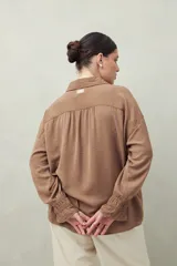 Camisa negra de manga larga con cuello clásico y botones frontales. El tejido presenta una textura arrugada o plisada, y los puños tienen un frunce elástico.