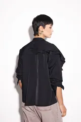 Camisa negra de nylon con cuello mao y volados de poliéster en el hombro.