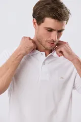 Remera polo piqué blanca de corte clásico, con cuello camisero, cierre frontal de dos botones y pequeño logo bordado en el pecho.