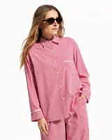Pijama de dos piezas de algodón a rayas celestes y blancas, compuesto por una camisa de manga larga con botones y ribetes marrones, y un pantalón largo de corte recto con elástico en la cintura.
