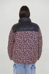 Campera puffer reversible de corte holgado, con cuello alto y cierre frontal. Un lado es de color azul vibrante con detalles en verde lima en el cierre y el interior, y el otro lado es de color negro.