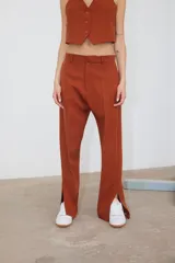 Pantalón de corte recto confeccionado en tela sastrera color ladrillo, con tajo lateral en la botamanga y bolsillos laterales.